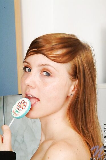 Red Haired Teen Babe Beth Nubiles Slowly Strips While Eating A Lollipop.