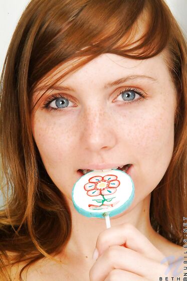 Red Haired Teen Babe Beth Nubiles Slowly Strips While Eating A Lollipop.